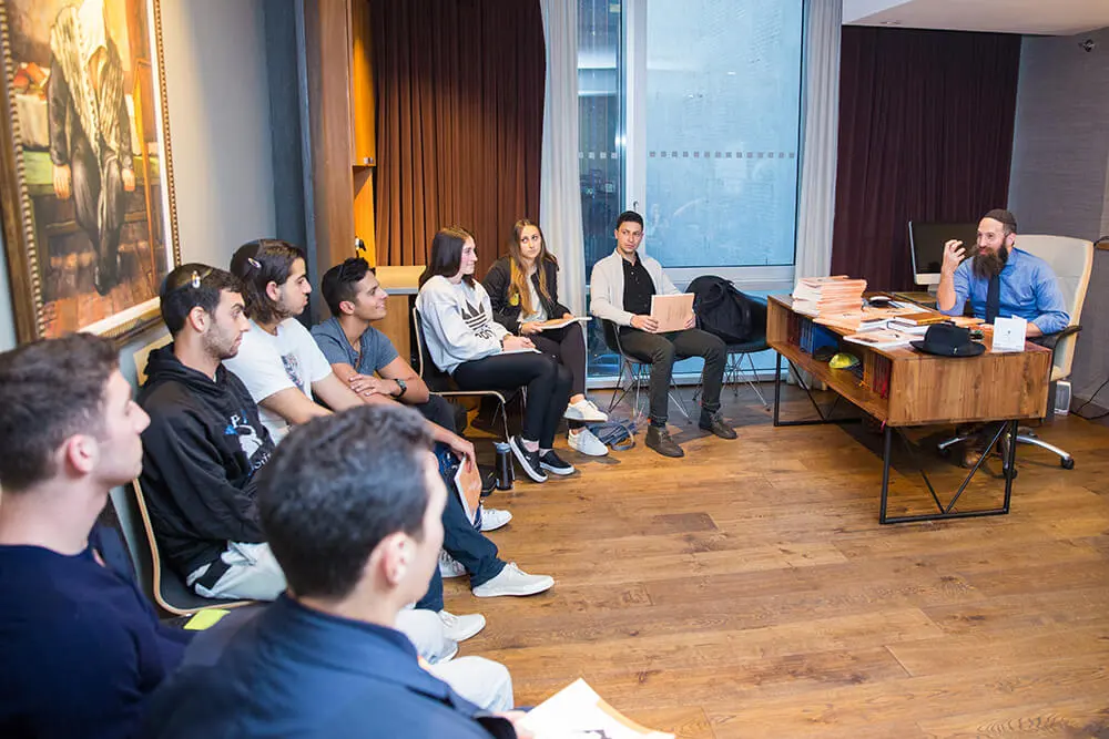 College students seated in a circle during a Jewish learning class at a Chabad House