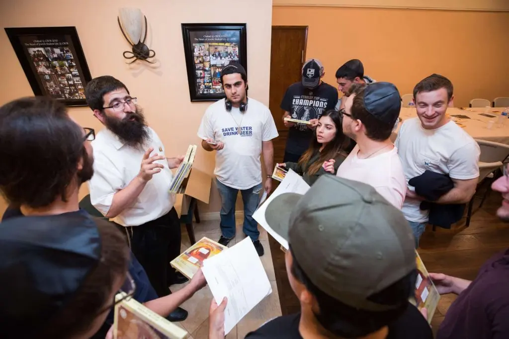 A Chabad rabbi learning with college students around a table